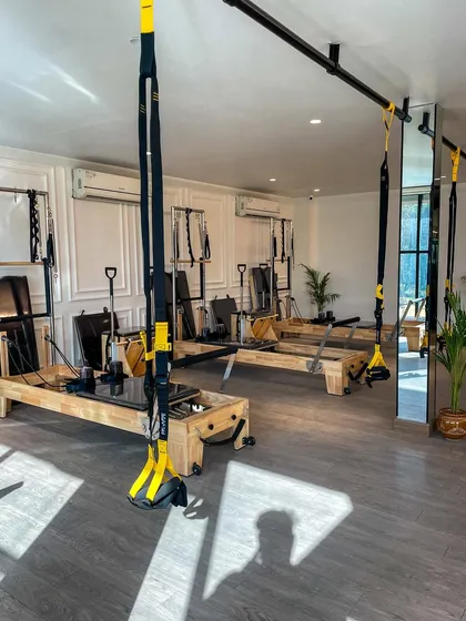 Our studio at Ramagya Sports Academy in Sector 50, featuring a clean, white aesthetic with TRX and Reformer equipment. The space is bright, airy, and designed for an ultimate Pilates experience.