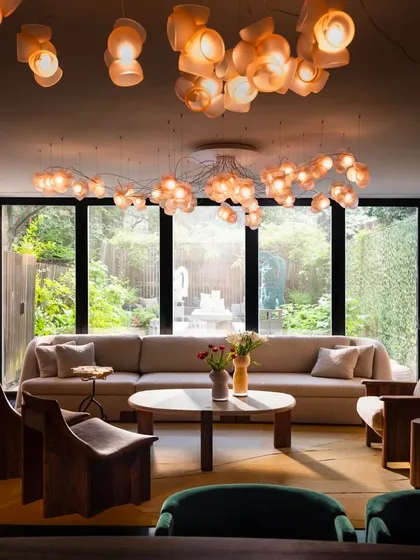 This view highlights the horizontal Bocci 100 installation over a modern living area. The fixture spans the length of the room, drawing the eye and connecting the different seating zones.