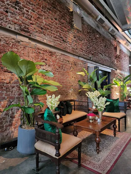 Even the seating areas were integrated into the green decor. Here, we placed tall, large-leafed plants behind traditional wooden furniture, using emerald green cushions to tie the whole look together. This approach ensures every corner of the event feels lush and thoughtfully designed.