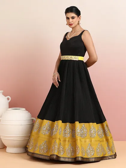 The side view of the black and gold gown showcases its flowing silhouette and the striking contrast of the border.