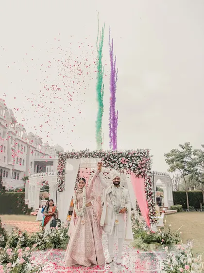 A grand celebration moment with the couple under a shower of petals and colorful smoke, creating a vibrant and joyful memory.