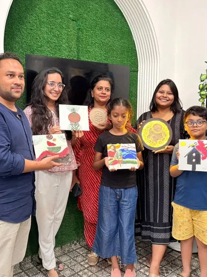 A family and friends group showing off their diverse paintings. Our workshops are for everyone, with no age bar for creativity.