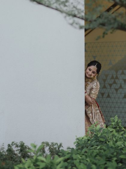 A playful peek from behind a wall, this candid shot captures the bride's joyful and fun-loving personality. It's these unscripted moments that add so much life to a wedding story.