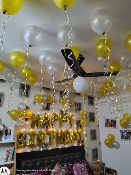 A closer look at the yellow and white birthday balloon setup. The balloons are arranged at different heights with curling ribbons, adding a playful touch to the room.