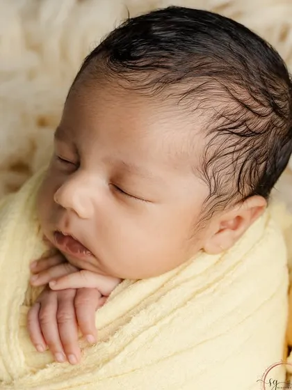 A close-up on the sleeping baby's face, highlighting their delicate features and the soft texture of the yellow wrap.