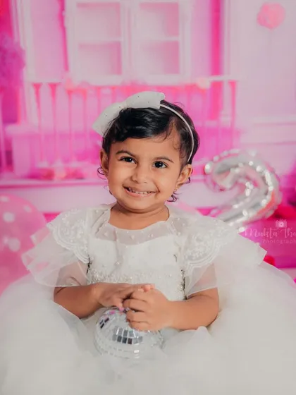 A dazzling smile from a two-year-old princess during her Barbie-themed birthday photoshoot. Her happiness truly lights up the entire studio.