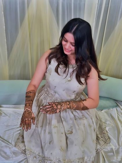 A candid moment of a client admiring her freshly applied, intricate mehandi.