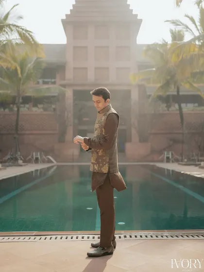 The groom, looking sharp and ready for the Mehendi ceremony, captured in a stylish portrait by the pool against a stunning architectural backdrop.