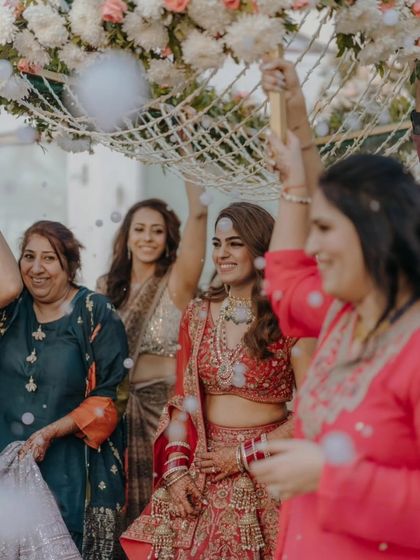A joyous moment during the bridal entry. The bride's smile is infectious, and her mehendi is a beautiful detail in this celebration of love and family.