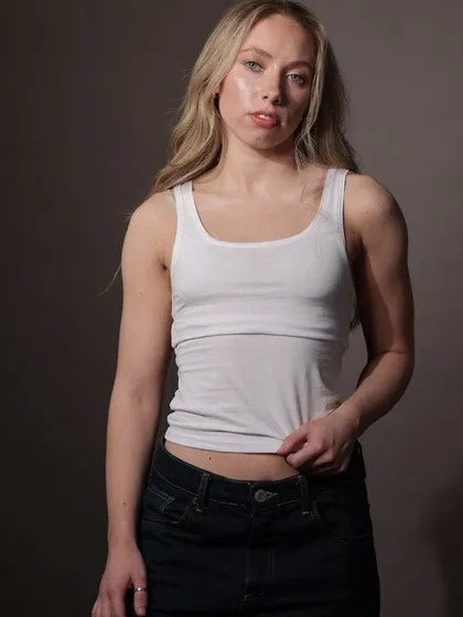 A simple and clean portrait of a model in a white tank top and jeans, demonstrating a natural and authentic look perfect for commercial or lifestyle portfolios.