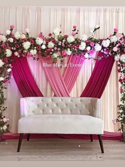 A stunning engagement stage with a floral arch in shades of pink and white. The layered pink drapes add depth and richness to the design, perfect for a grand celebration.