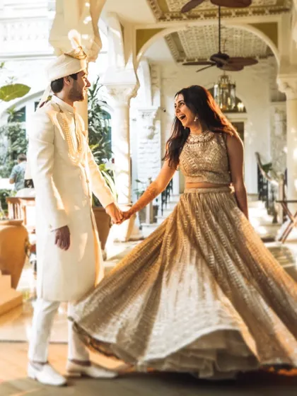A candid moment of joy and movement. The bride's swirling lehenga and the couple's happy expressions make this a lively and beautiful wedding portrait.
