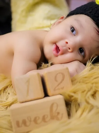 Marking the early weeks with wooden milestone blocks. This baby, dressed in a bee costume, shows how we can track your baby's growth even in the first month.