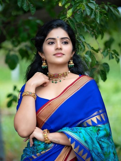 This portrait of Megha Shetty showcases the beautiful color combination of her saree against the lush green background.