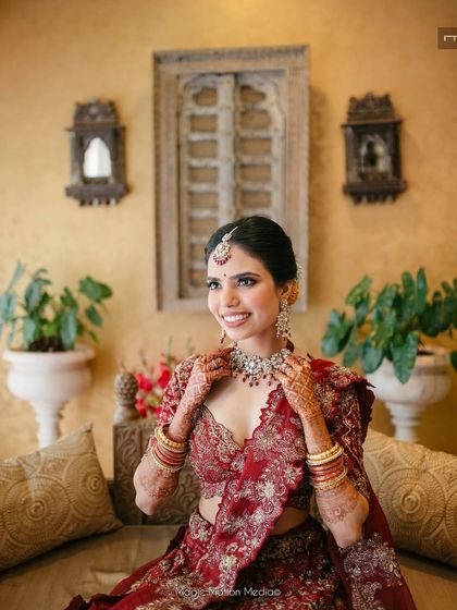 This bride's look is a beautiful blend of traditional and contemporary. The makeup is soft and glamorous, perfectly suiting her intricately embroidered maroon lehenga.