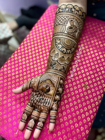 A detailed bridal mehendi with peacocks on the palms and elephants on the wrists. The fine line work and shading add depth and dimension to the design.