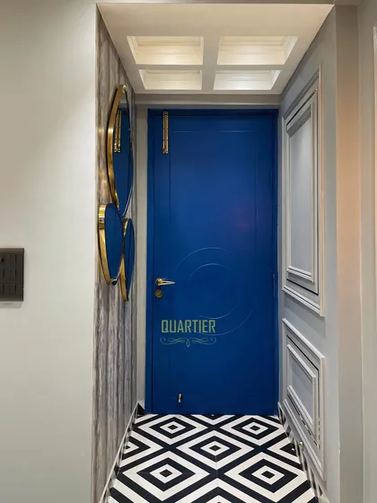 The entrance foyer at the Elite Golf Greens project makes a bold statement with its vibrant blue door and black-and-white geometric floor tiles. The design immediately establishes the home's unique, modern European character.