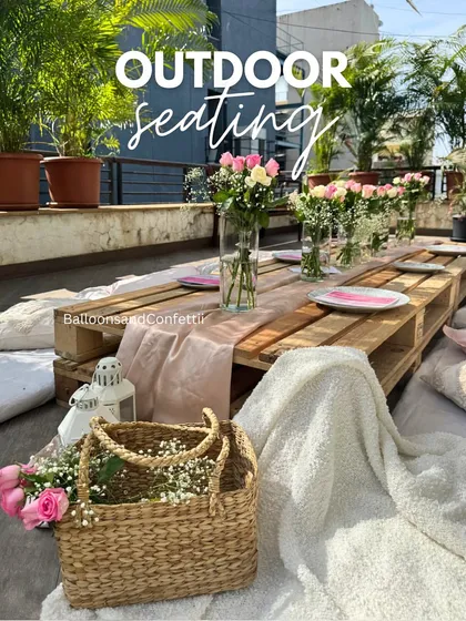 A closer look at the outdoor picnic seating. The low pallet table is adorned with a simple runner, fresh flowers, and comfortable cushions for a relaxed vibe.