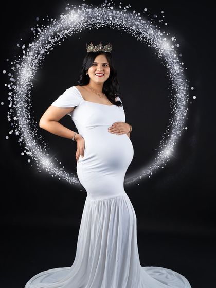 A magical portrait using a ring of light to frame the mom-to-be in her elegant white gown. This creative lighting effect adds a touch of sparkle and wonder to the classic black-background studio shot.