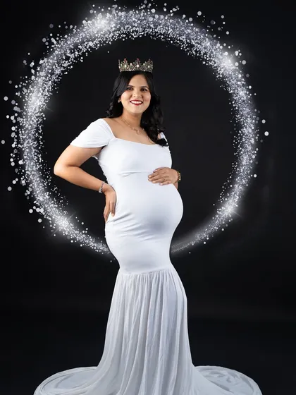 A magical portrait using a ring of light to frame the mom-to-be in her elegant white gown. This creative lighting effect adds a touch of sparkle and wonder to the classic black-background studio shot.