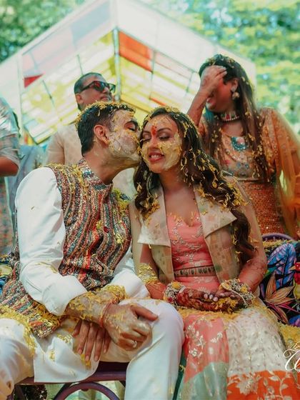 A Haldi ceremony is about blessings and a lot of fun. This candid shot captures the couple sharing a sweet moment amidst the playful chaos of being covered in turmeric and flowers.