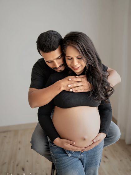 An intimate moment showing the couple's connection to their baby. Both parents' hands are on the bump, a simple and powerful symbol of their shared journey.