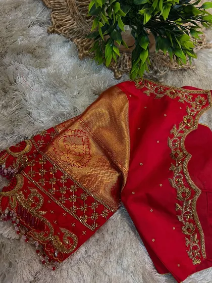 This is the kind of craftsmanship you will learn to create. This vibrant red bridal blouse features intricate gold Aari work along the neckline and sleeves, combined with traditional brocade fabric for a timeless look.