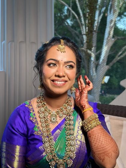 A happy, candid shot showing the complete look with the vibrant blue and green saree.
