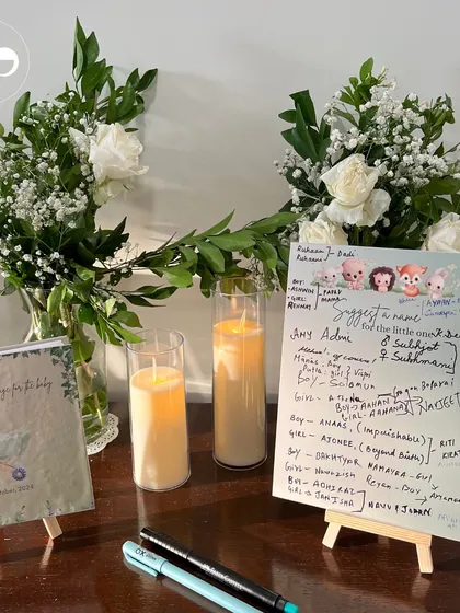 Guests filled this board with sweet name suggestions for the little one. This interactive element, set amongst beautiful white roses and candles, became a cherished keepsake from their intimate home celebration.