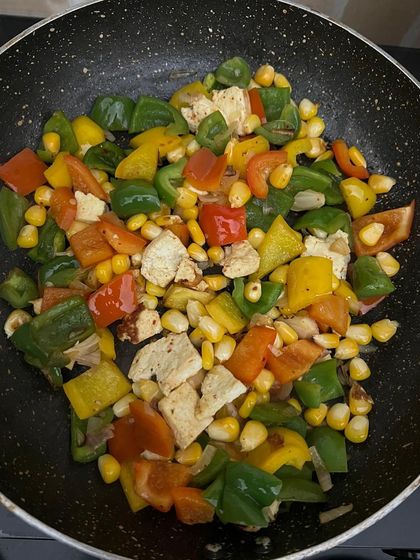 A pan of sautéed bell peppers, corn, and paneer. This is a versatile dish that can be eaten on its own or as a side.