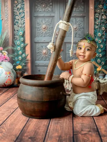 A playful moment captured as baby Krishna tries to churn butter.