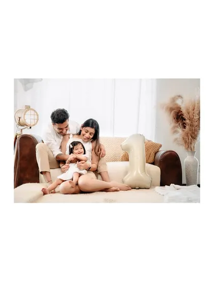 Celebrating a first birthday with a cozy family photo on the couch. The "1" balloon adds a festive touch to this intimate and loving portrait.