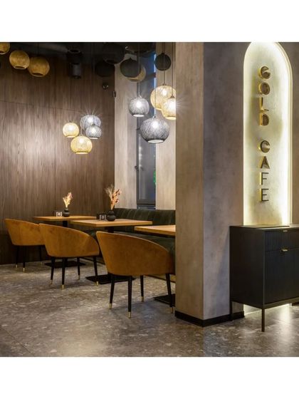 A quiet corner of the cafe, perfect for small groups. The design uses a mix of dark wood paneling and textured grey walls to create a warm and modern space.