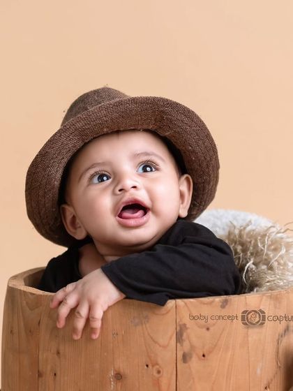 A cute baby peeking out of a wooden barrel with a hat on. This is a simple yet adorable prop setup for a milestone session.