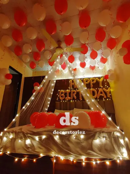 A clear shot of the red and white birthday room decor. The combination of the light canopy, foil balloons, and numerous loose balloons creates a very full and festive look.