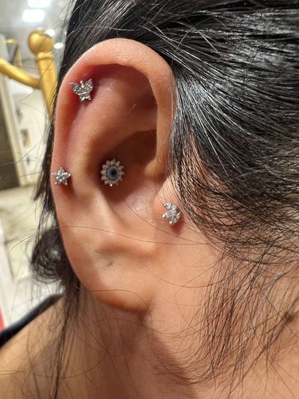 This stack combines multiple piercing types, including a flat helix, conch, and tragus, all adorned with delicate silver studs for a subtle yet full look.
