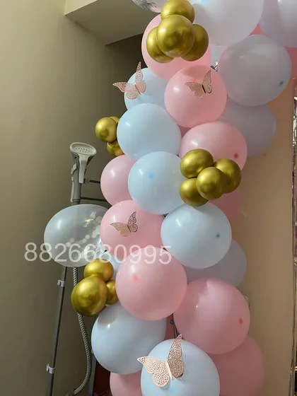 A detail shot showing the small touches, like these delicate paper butterflies added to the pink, white, and gold balloons for a softer look.