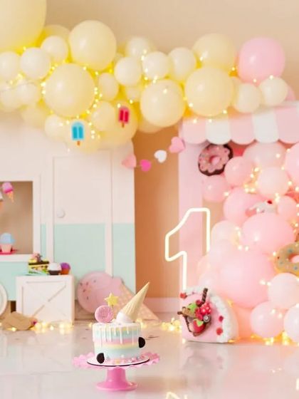 A sweet and whimsical pastel ice cream shop theme for a first birthday. This adorable setup includes a custom-built ice cream cart, donut and cupcake props, and soft, dreamy lighting.