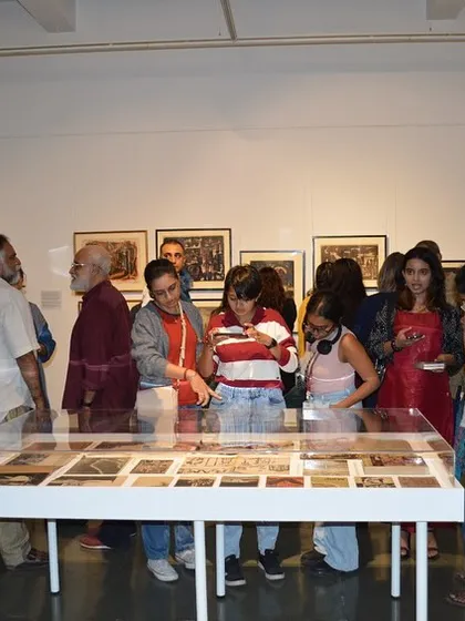 Visitors gathered around the vitrine of archival materials at the 'Hand Prints' preview.
