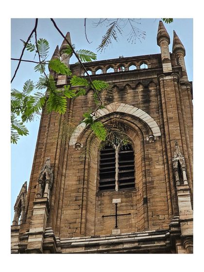 Another angle of the church tower, with green leaves providing a natural frame for the architecture.