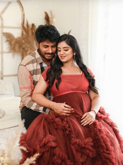 An intimate couple's portrait in a warm, boho chic studio setting. The rich red of her dress adds a pop of color and romance.
