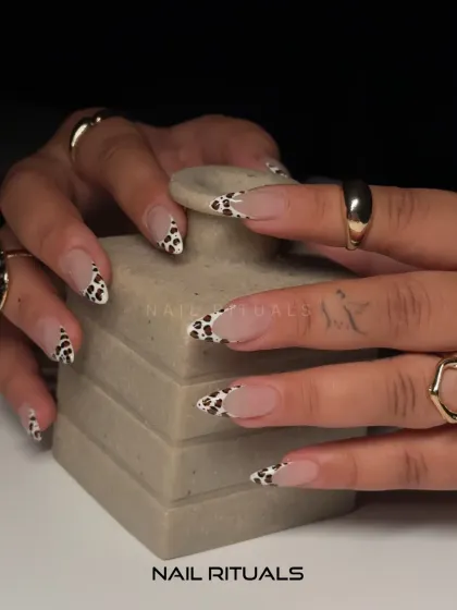 Wild, chic, and oh-so-trendy. This close-up shot highlights the detail of our cow print French tips on almond-shaped nails.
