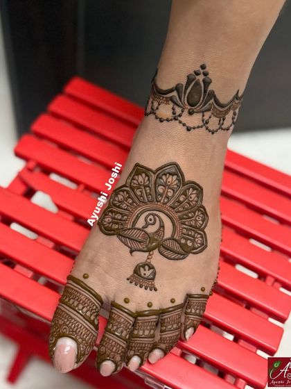 An elegant foot mehendi with a large peacock motif and a simple lotus anklet, perfect for a bride who wants a modern look.