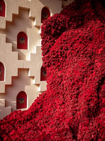 A close-up of the massive red 'Baoli' installation, revealing the texture of the thousands of Sola wood flowers. The sheer density and scale of the piece transform the material into a powerful, monolithic sculpture.