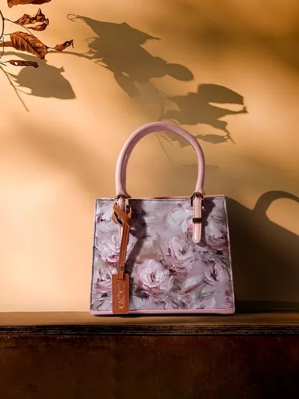 A beautiful shot using light and shadow to create a dramatic effect. The shadow of leaves falls across a floral handbag, adding depth and artistry to the composition.