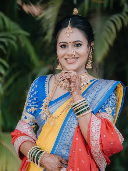 A portrait of a beautiful bride in a classic yellow and blue Paithani saree.