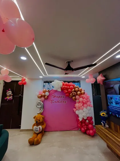 A wider shot of the room, showing the birthday backdrop and additional balloons on the ceiling.