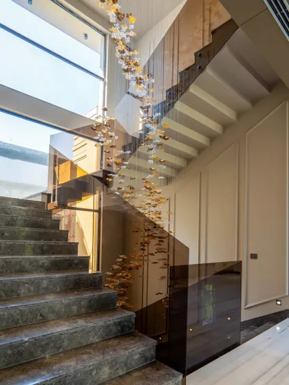 The staircase in the Sultanpur farmhouse is a journey in itself. The custom chandelier cascades down the center, while the contrast of dark stone steps and light walls adds to the neo-classical drama and elegance.