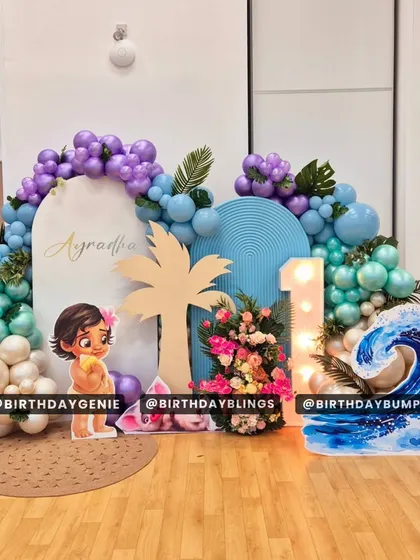 This Moana first birthday party features a beautiful wave cutout and a light-up number '1'. The color palette of purple, teal, and white captures the spirit of the ocean.