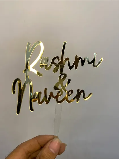 A simple and classic topper with the names "Rashmi & Naveen" in a beautiful flowing script.